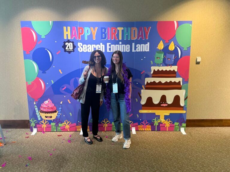 May and Olivia at SMX Boston conference by a Happy Birthday Search Engine Land sign
